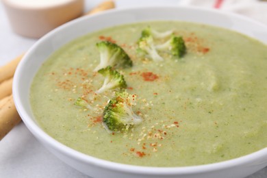 Photo of Delicious broccoli cream soup served on light table, closeup