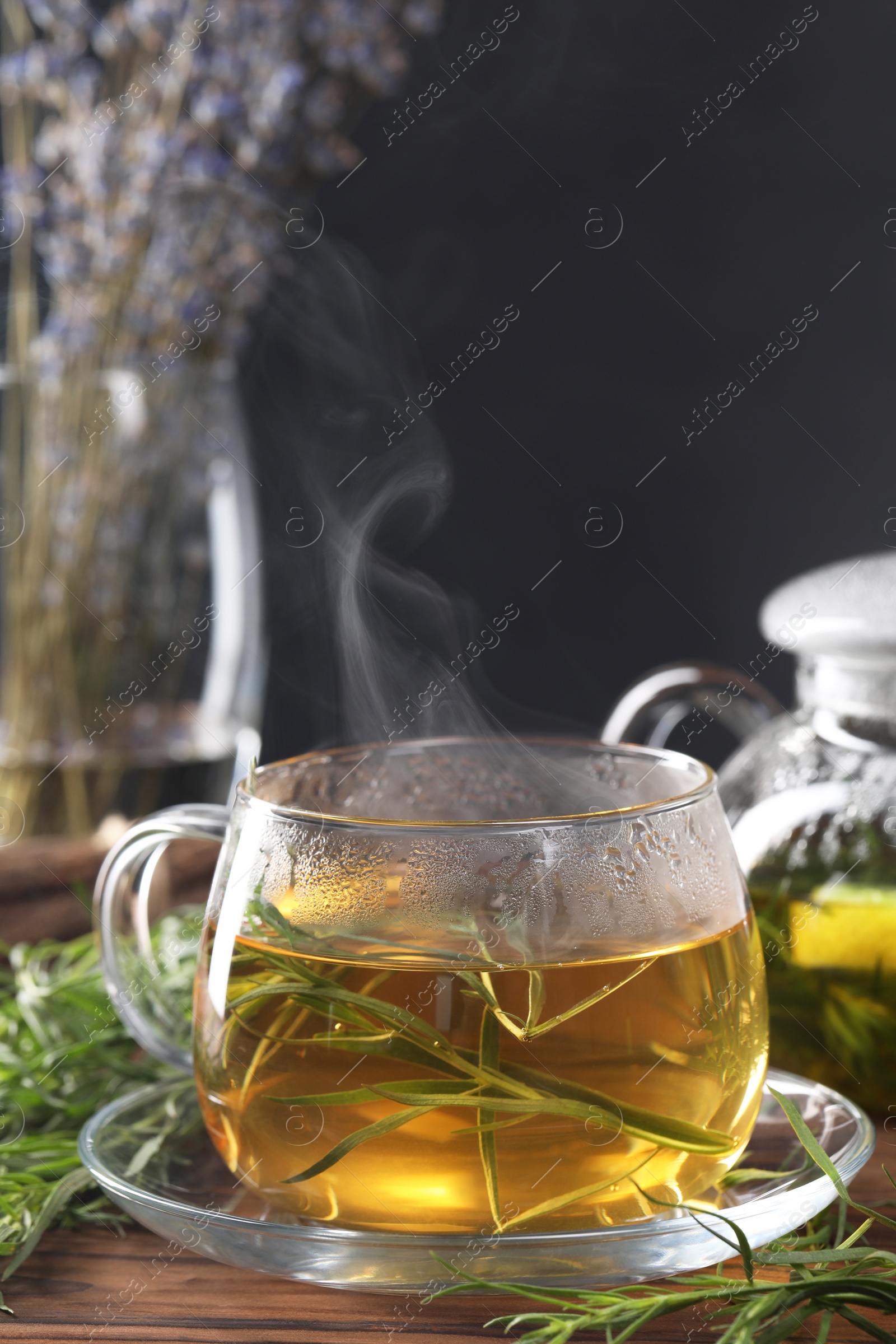 Photo of Homemade herbal tea and fresh tarragon leaves on wooden table