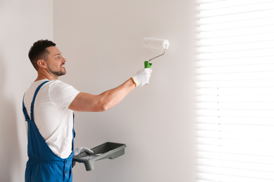 Man painting wall with white dye indoors