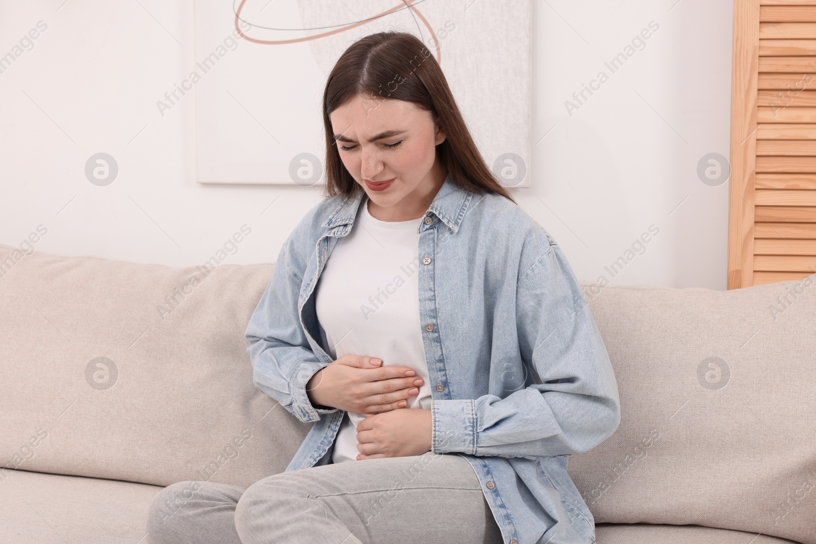 Photo of Young woman suffering from stomach pain at home