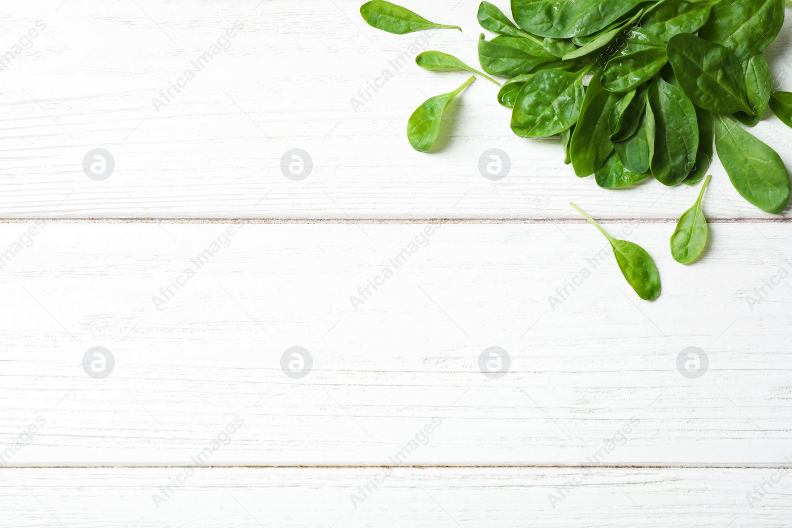 Photo of Heap of fresh green healthy spinach on white wooden table, top view. Space for text