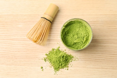 Powdered matcha tea and chasen on wooden background, top view