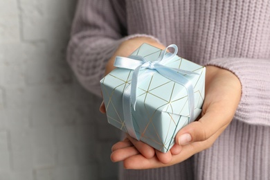 Photo of Young woman holding Christmas gift on light background, closeup