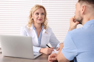 Photo of Doctor consulting patient at table in clinic