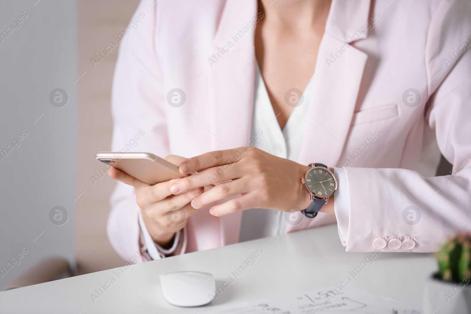 Photo of Young woman with wristwatch and smartphone at workplace. Time management