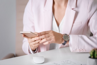 Young woman with wristwatch and smartphone at workplace. Time management