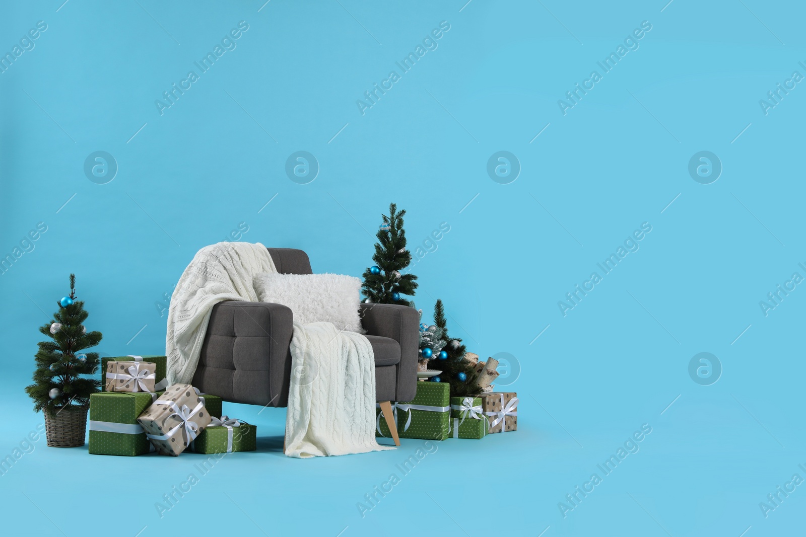 Photo of Beautiful Christmas themed photo zone with stylish armchair, trees and gift boxes in studio