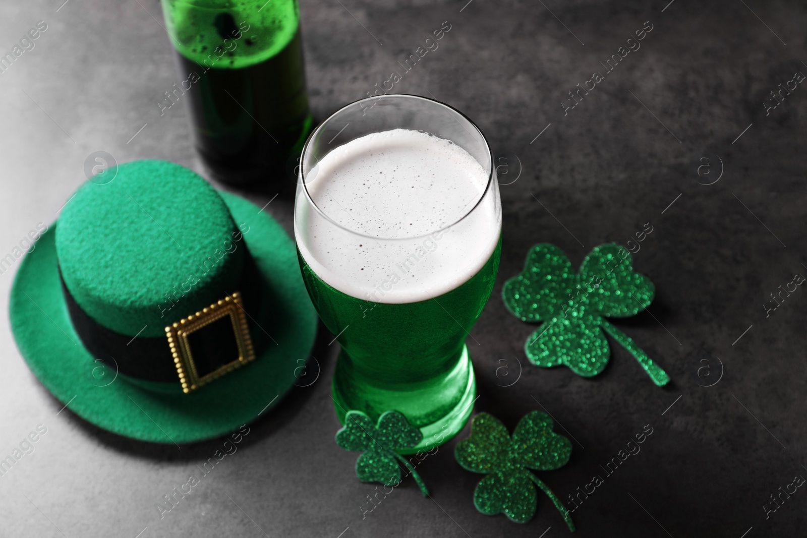 Photo of St. Patrick's day celebration. Green beer, leprechaun hat and decorative clover leaves on grey table