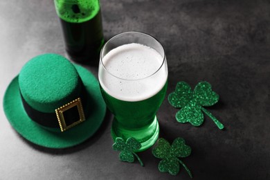 Photo of St. Patrick's day celebration. Green beer, leprechaun hat and decorative clover leaves on grey table