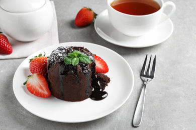 Delicious warm chocolate lava cake with mint and strawberries on table