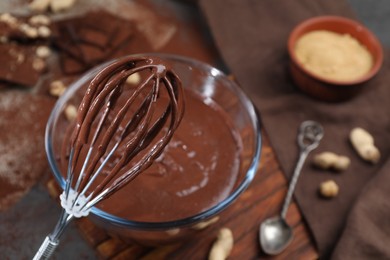 Whisk with chocolate cream above bowl, closeup