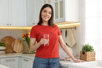 Photo of Young woman with glass of water in kitchen