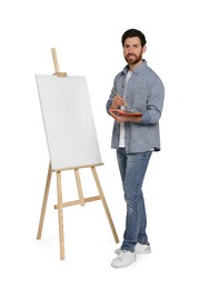 Happy man with brush and artist`s palette near easel with canvas against white background. Creative hobby