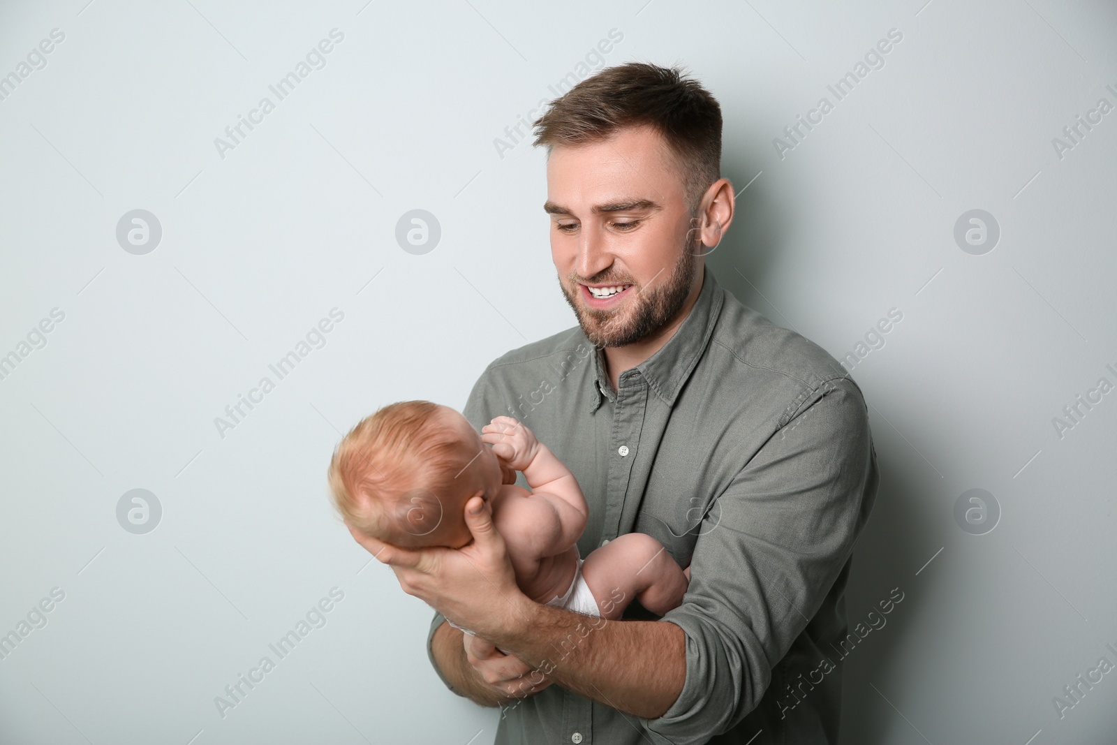 Photo of Father with his newborn son on light grey background