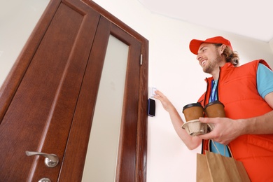 Photo of Male courier with order ringing in doorbell at entrance. Food delivery service