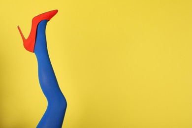 Photo of Woman wearing blue tights and high heel shoe on yellow background, closeup. Space for text
