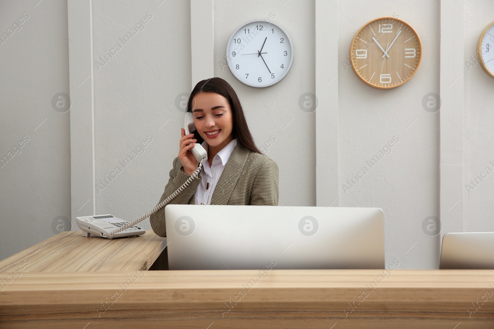 Photo of Beautiful receptionist talking on phone at counter in hotel