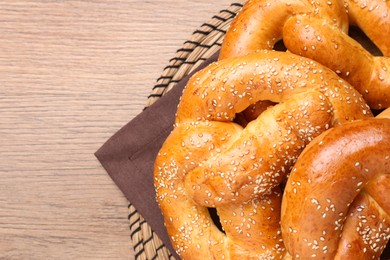 Delicious pretzels with sesame seeds on wooden table, top view. Space for text