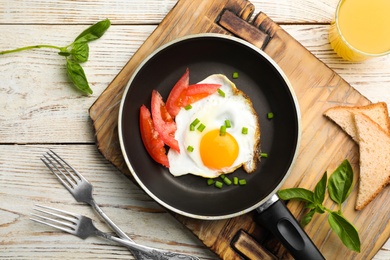 Photo of Fried sunny side up egg with tomato in pan served on table, flat lay