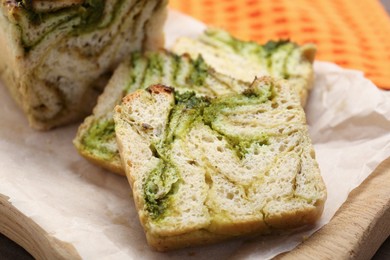 Photo of Slices of freshly baked pesto bread on wooden board, closeup