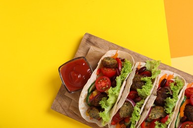 Many delicious vegetarian tacos served on yellow table, top view