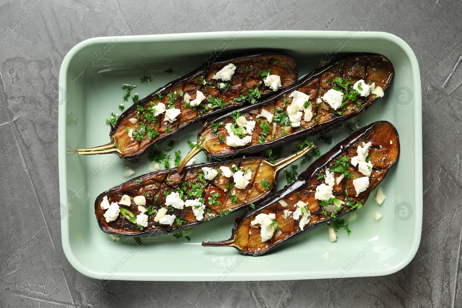 Photo of Baking dish with fried eggplant slices on grey background, top view