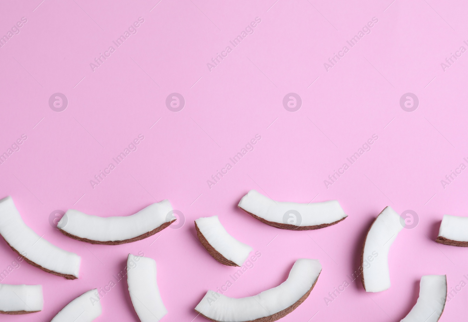 Photo of Fresh coconut pieces on pink background, flat lay. Space for text