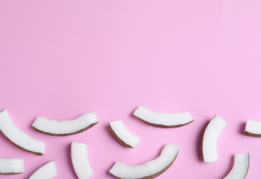 Fresh coconut pieces on pink background, flat lay. Space for text