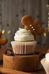 Tasty Christmas cupcake with gingerbread man cookie on wooden table