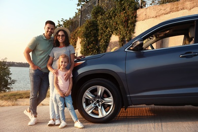 Happy young family near car on riverside