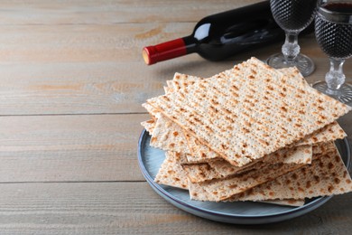 Photo of Stack of traditional matzos and red wine on wooden table, space for text