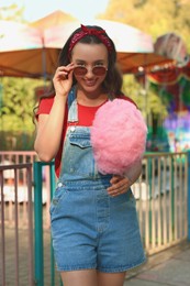 Photo of Stylish young woman with cotton candy outdoors