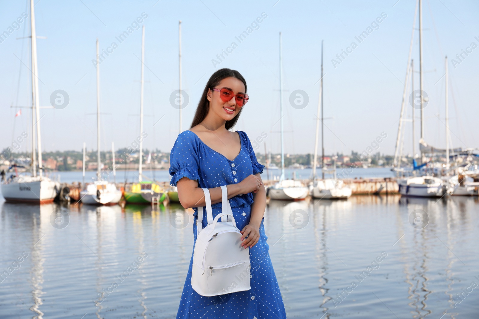 Photo of Beautiful young woman with stylish backpack near river