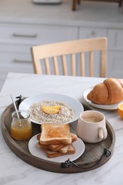 Wooden tray with delicious breakfast on table