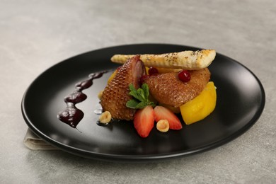 Photo of Plate with delicious chicken, parsnip and strawberries on grey table. Food stylist
