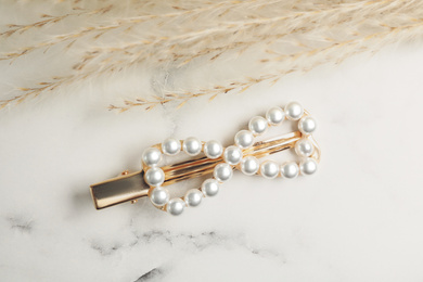 Beautiful gold hair clip and spikelets on white marble table, flat lay