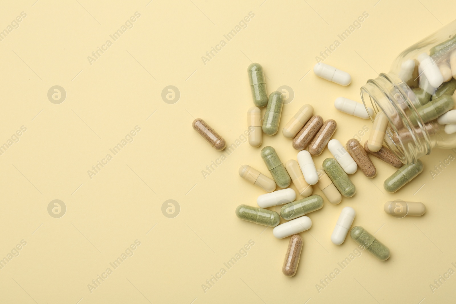 Photo of Vitamin pills and bottle on beige background, top view. Space for text