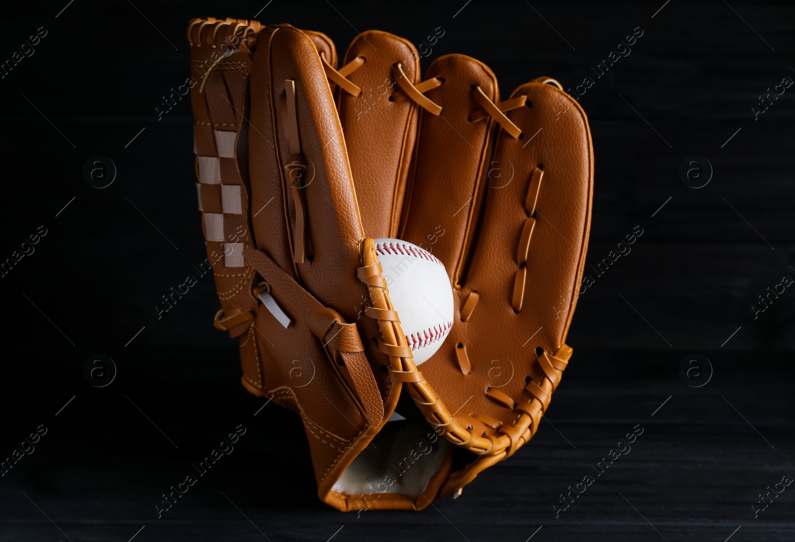 Photo of Catcher's mitt and baseball ball on black background. Sports game