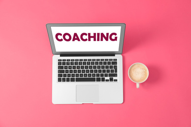 Business training or life coaching. Modern laptop and cup of coffee on pink background, flat lay