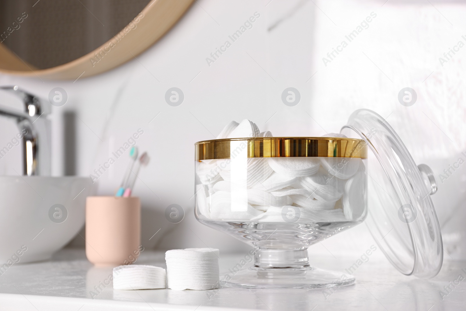 Photo of Glass jar with cotton pads on table in bathroom. Space for text