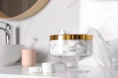 Glass jar with cotton pads on table in bathroom. Space for text