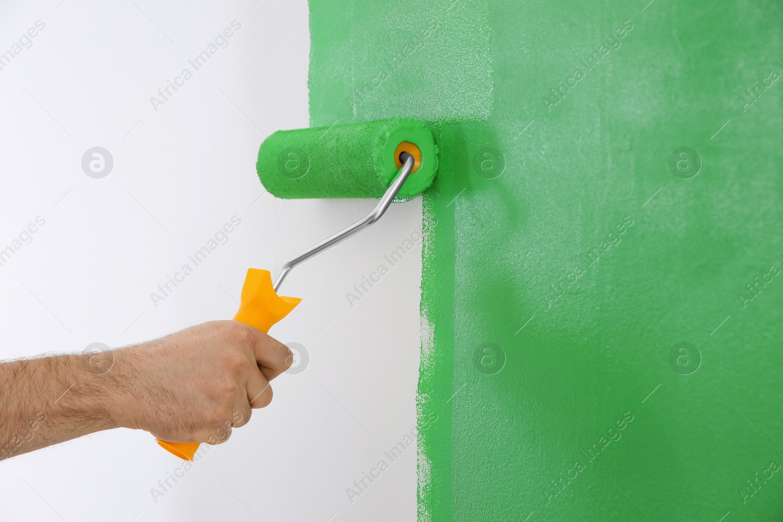 Photo of Man painting white wall with green dye, closeup. Interior renovation