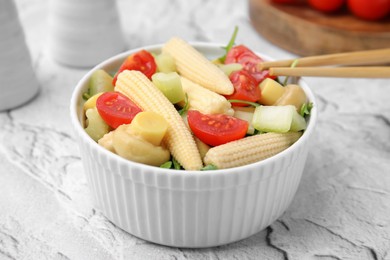 Photo of Tasty baby corn with vegetables and champignons on grey textured table, closeup