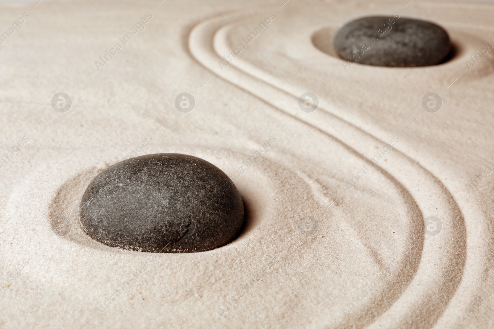 Photo of Zen garden stones on sand with pattern. Meditation and harmony