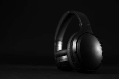 Photo of Modern wireless headphones on black background, space for text