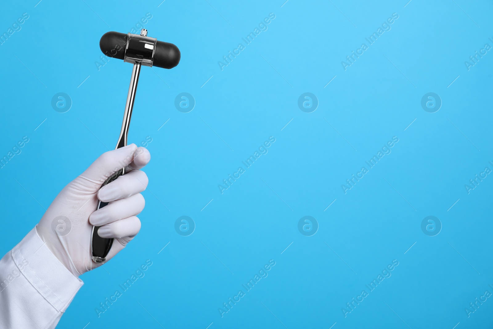 Photo of Doctor holding reflex hammer on light blue background, closeup with space for text. Nervous system diagnostic