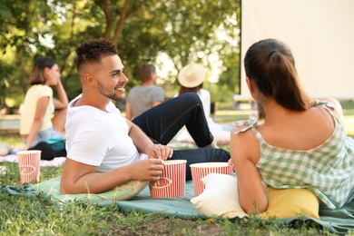 Young couple with popcorn watching movie in open air cinema. Space for text