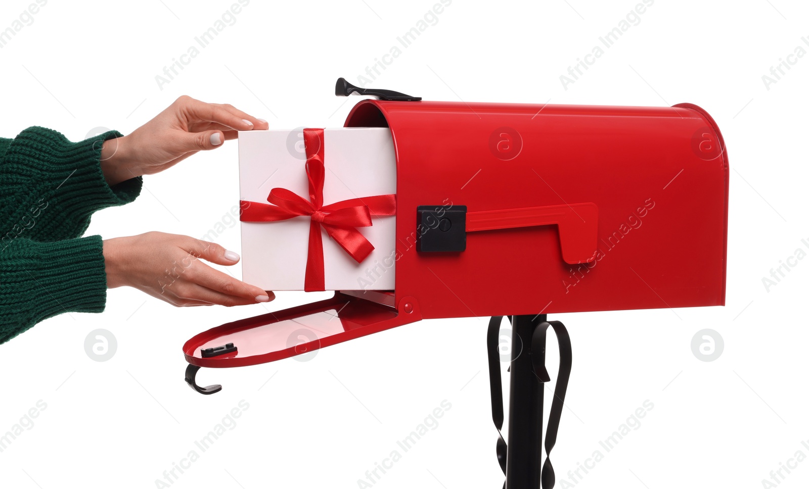 Photo of Woman putting Christmas gift into mailbox on white background, closeup. Sending present by mail