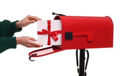 Photo of Woman putting Christmas gift into mailbox on white background, closeup. Sending present by mail