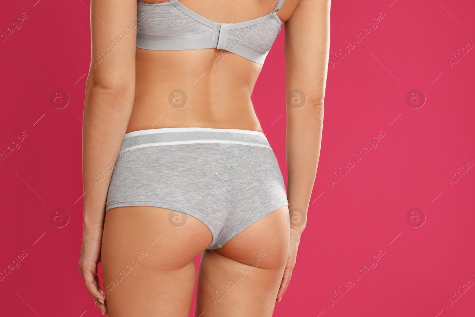 Photo of Young woman in grey sportive underwear on pink background, closeup